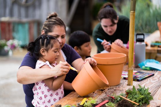 an adult and child painting a terra cotta pot